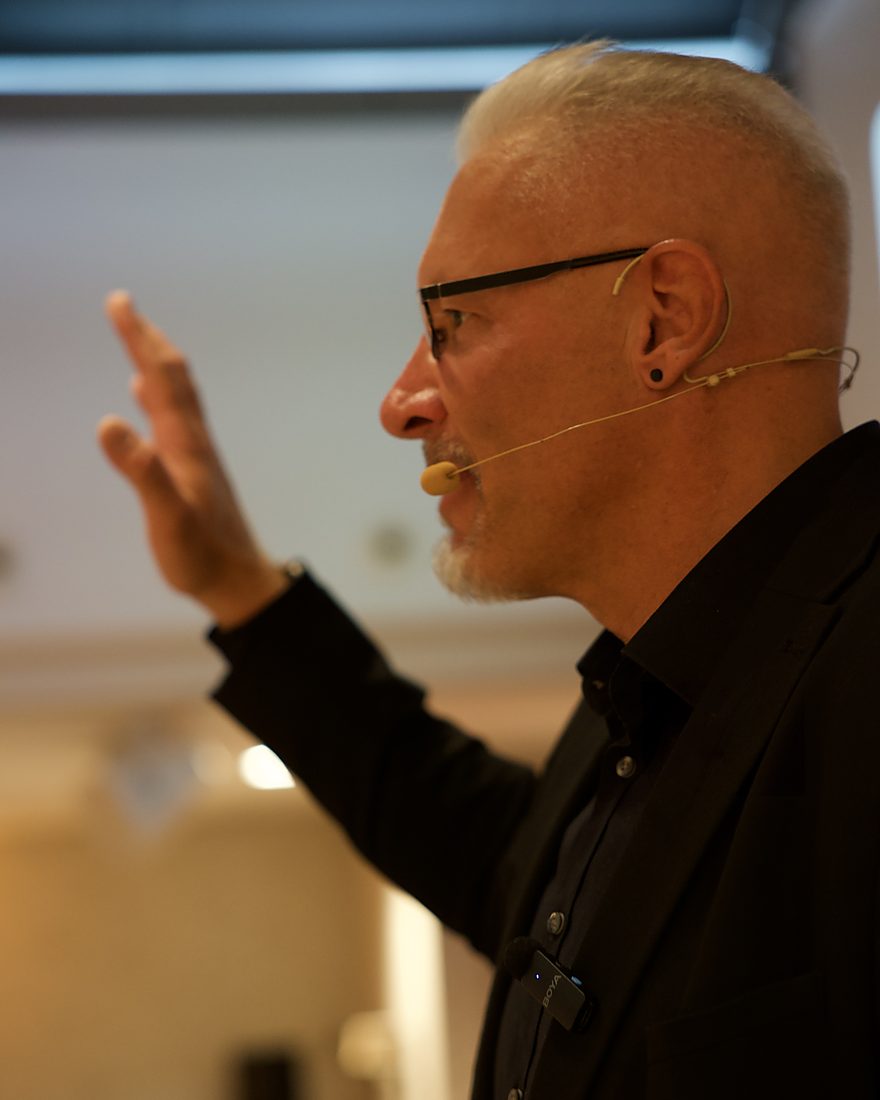 Reiner Küstner erklärt im Seminar mit erhobener Hand