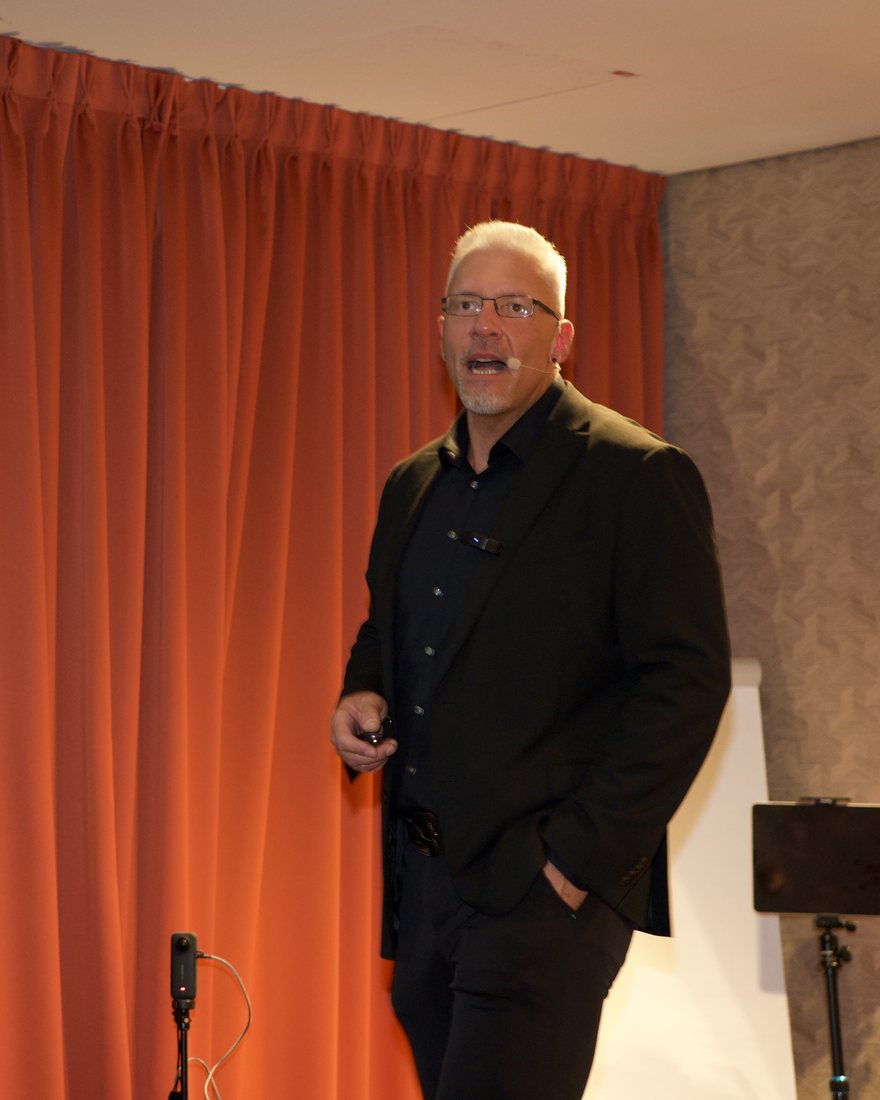Reiner Küstner auf der Bühne vor einem roten Vorhang
